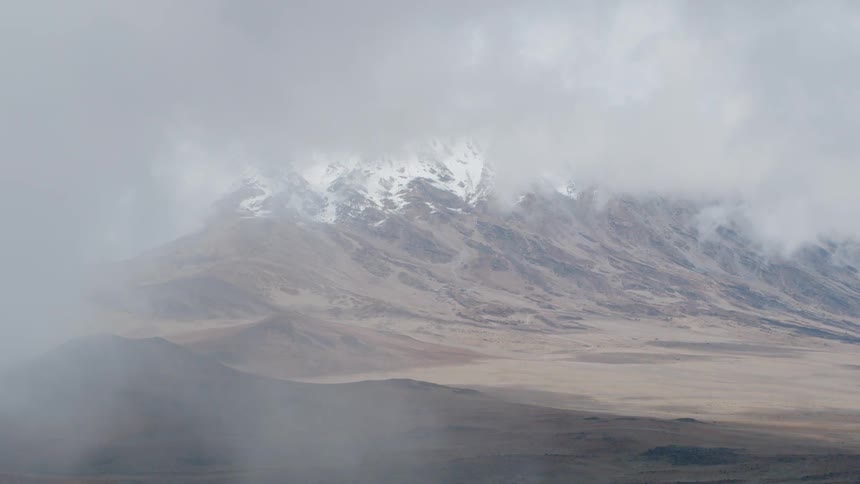 Clouds float over snowy mountains