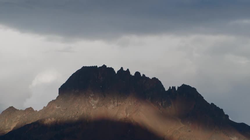 The heavy storm clouds put a shadow on the mountain