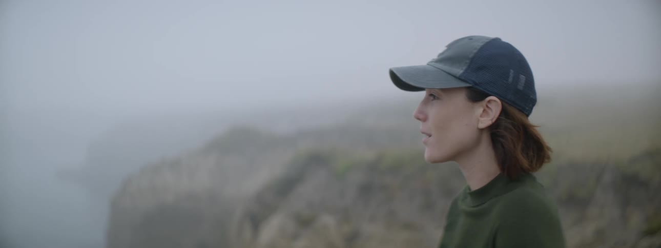 A woman looks out onto the water from a cliff