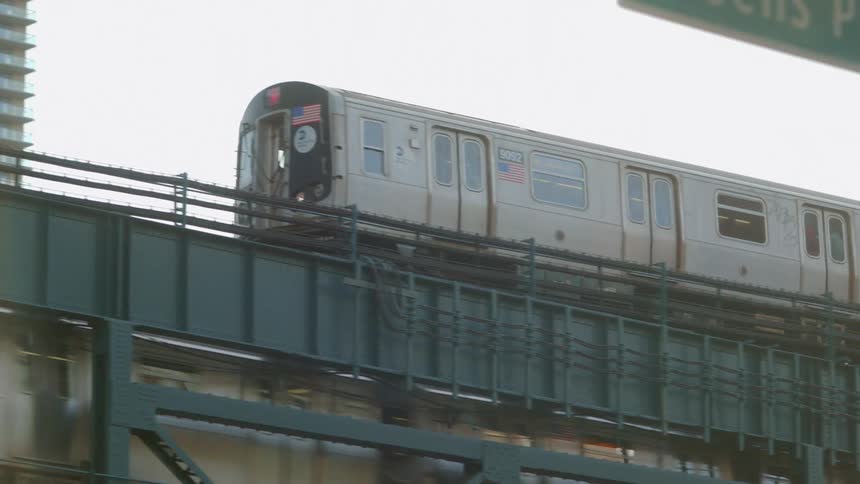 Two trains are traveling in opposite directions above a street