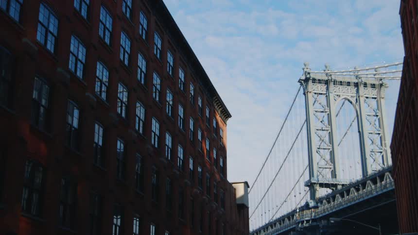 Vehicles pass over a city bridge near a large brick building