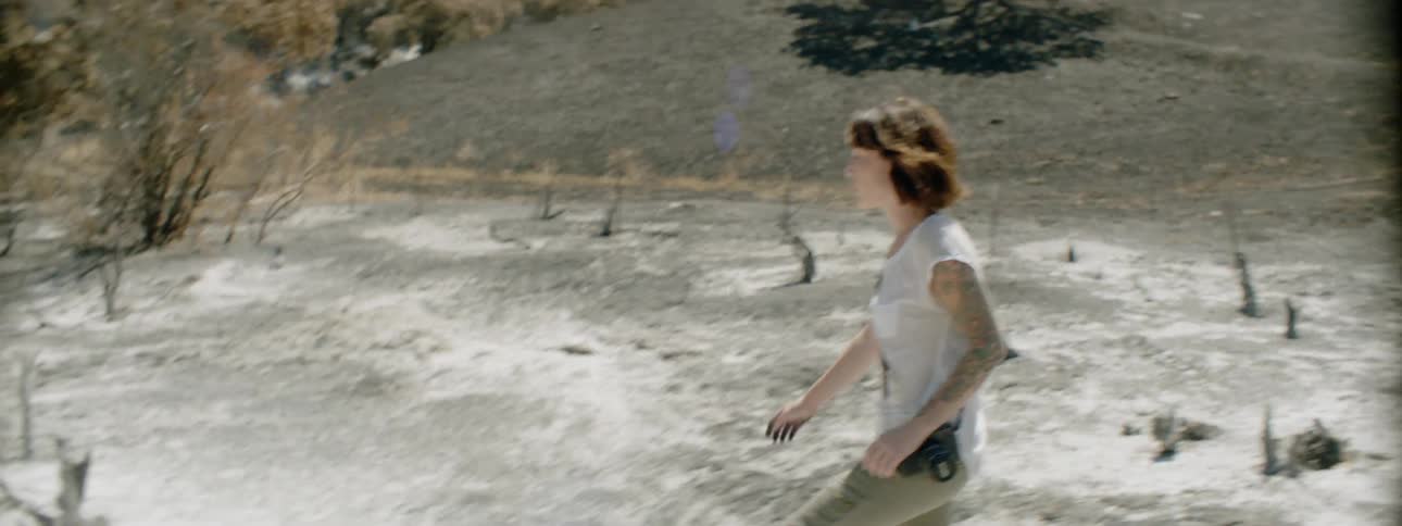 A woman walks through land damaged by fire