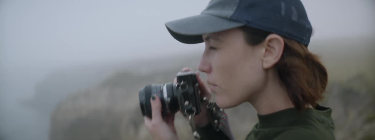 A woman takes a photograph on a foggy day