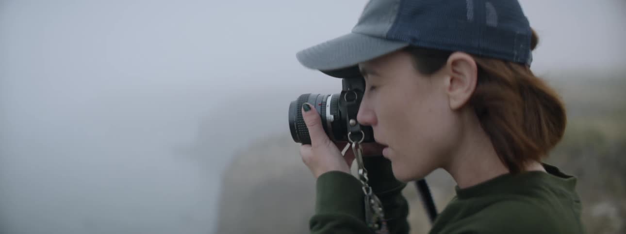 A woman takes a photograph of the water from a cliff