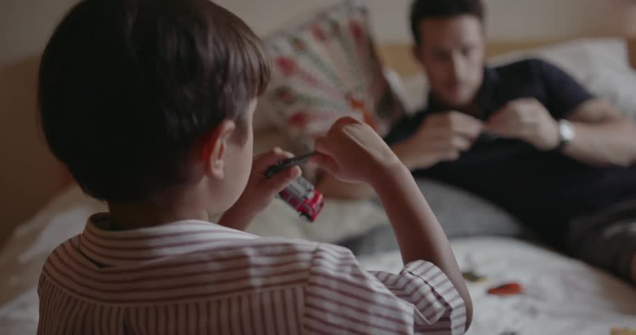A man and child play with toy cars