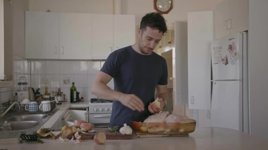 A man cooks a chicken and potatoes at home