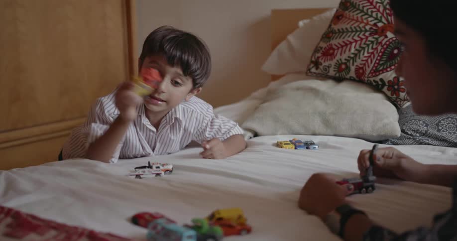 A child and mother play with toys on the bed