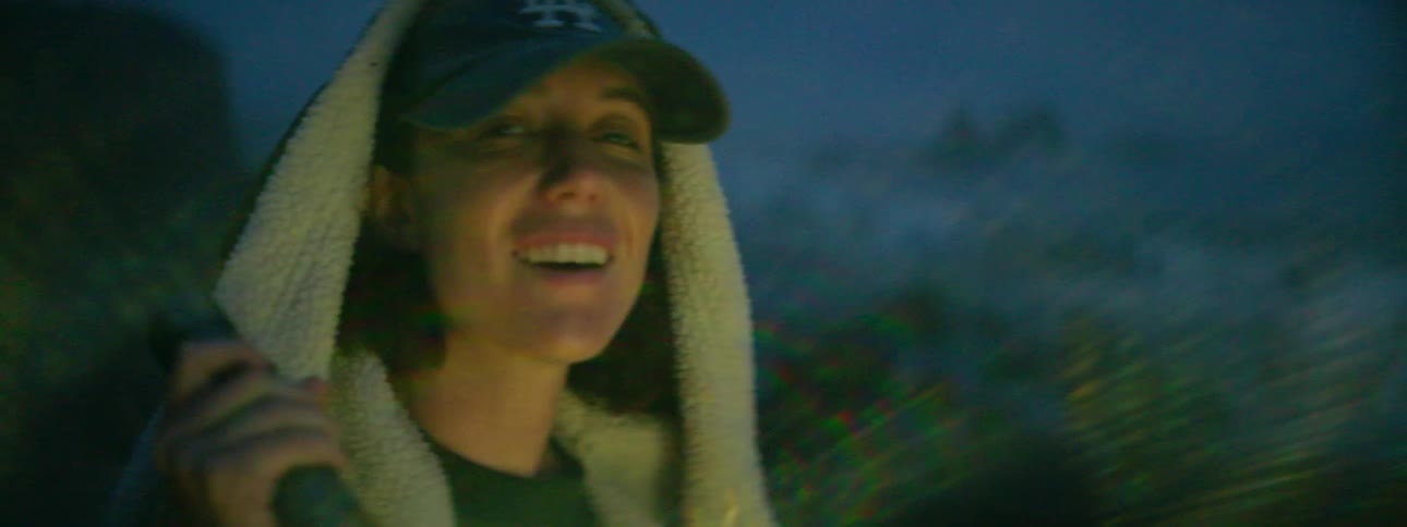 A woman uses a flashlight on the beach at night