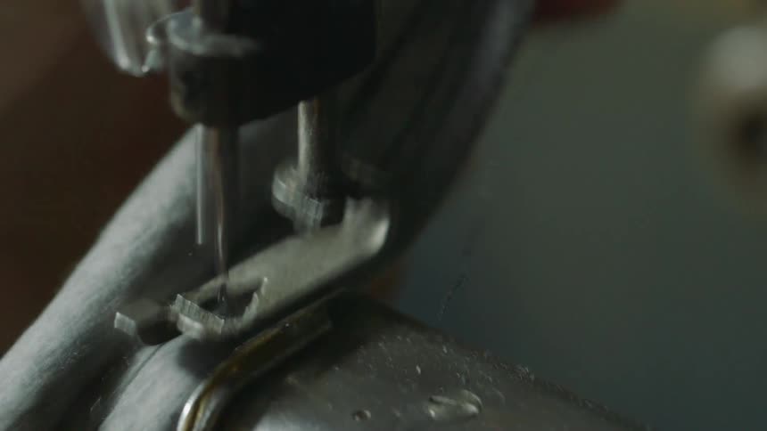 Hand feeds cloth through a sewing machine and the needle moves rapidly