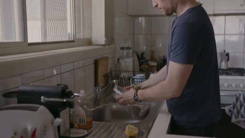 Man washes a glass in the sink