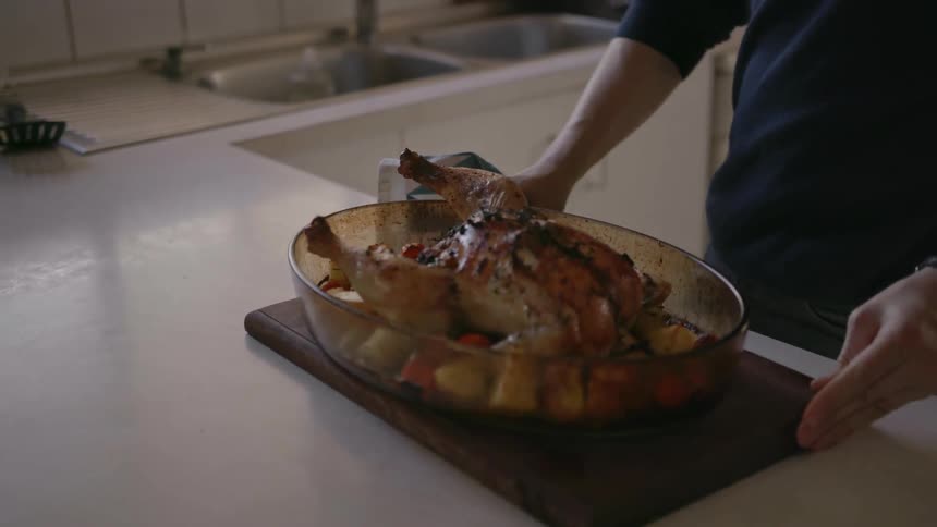 A man has taken a roasted chicken out of the oven