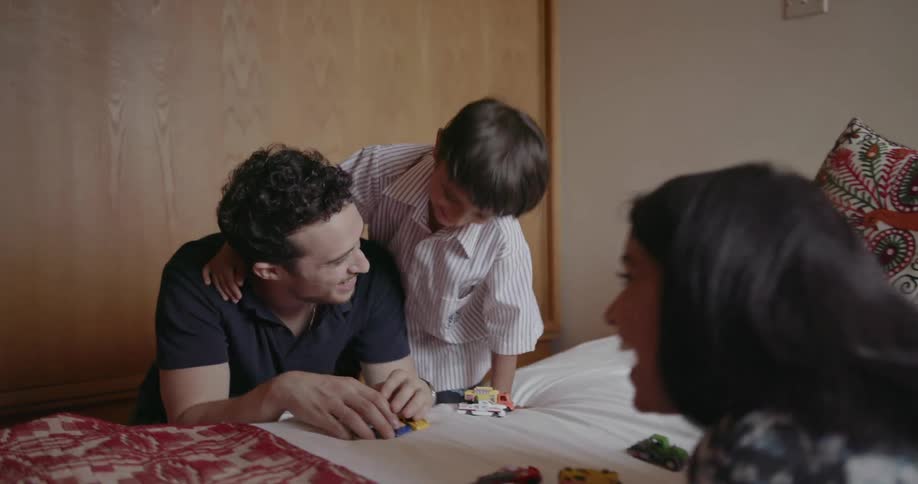 A family plays with toys on a bed