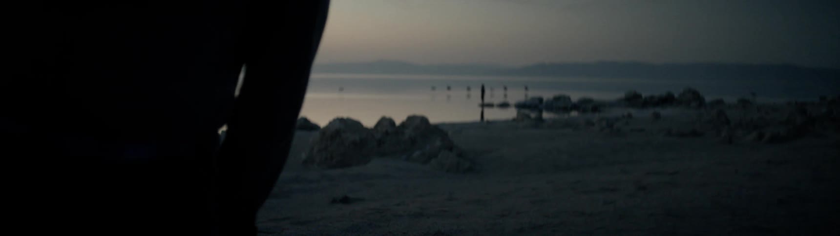 Person walks along beach at sunrise