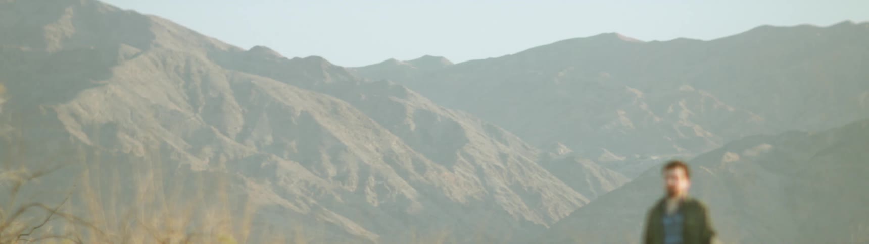 Man walks near rocky mountains on a sunny day