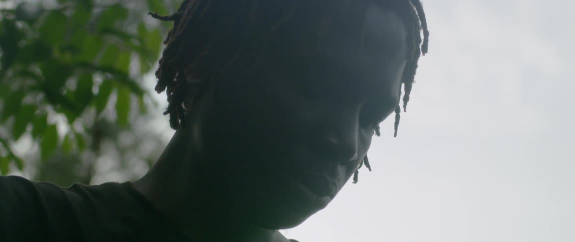 Man looking solemnly downwards outdoors on a cloudy day