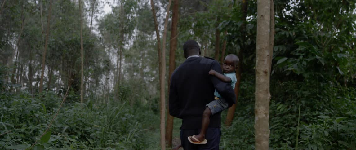 A man carries a child in the forest