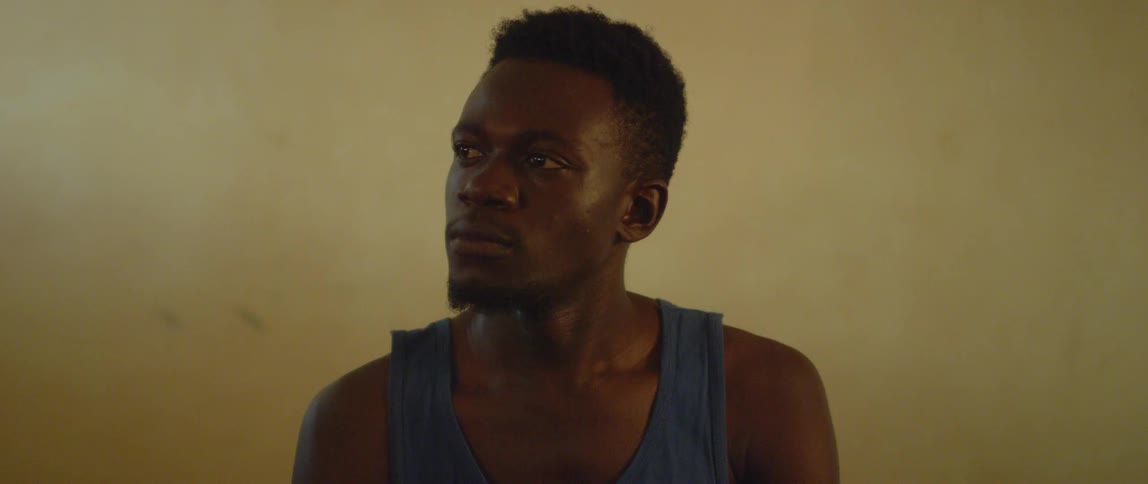 A man in a purple tank top stares to his side