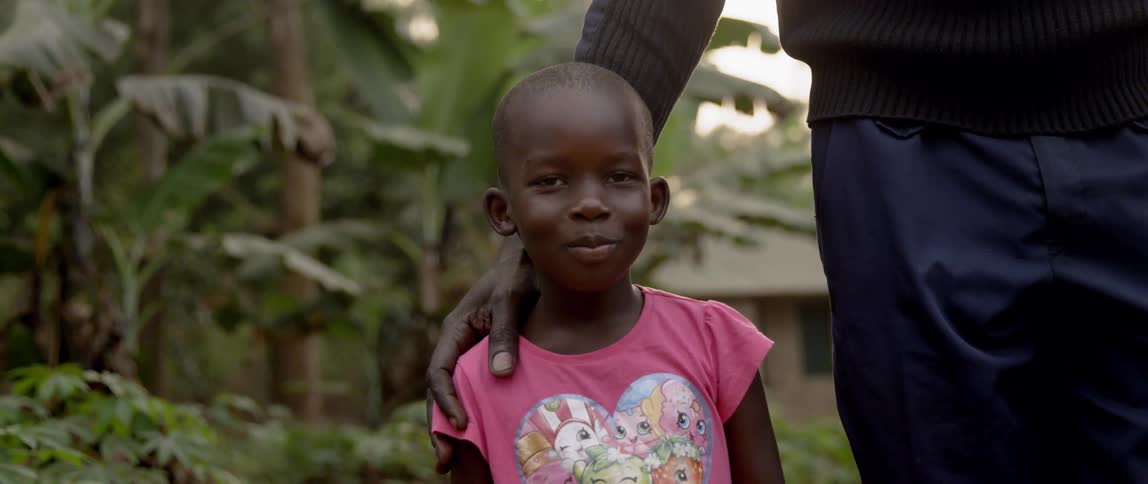 A child is smiling standing next to someone