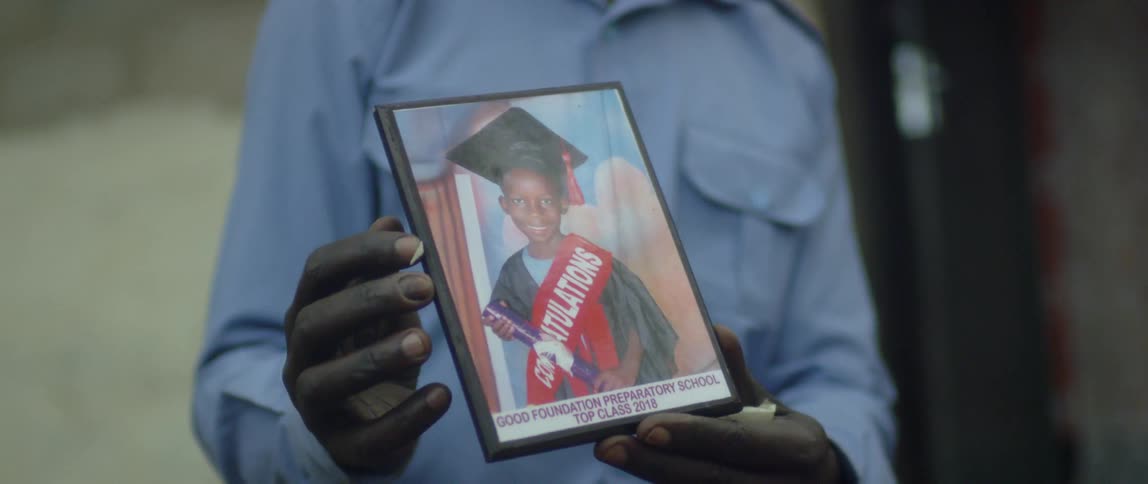 A man holds a framed graduation photograph