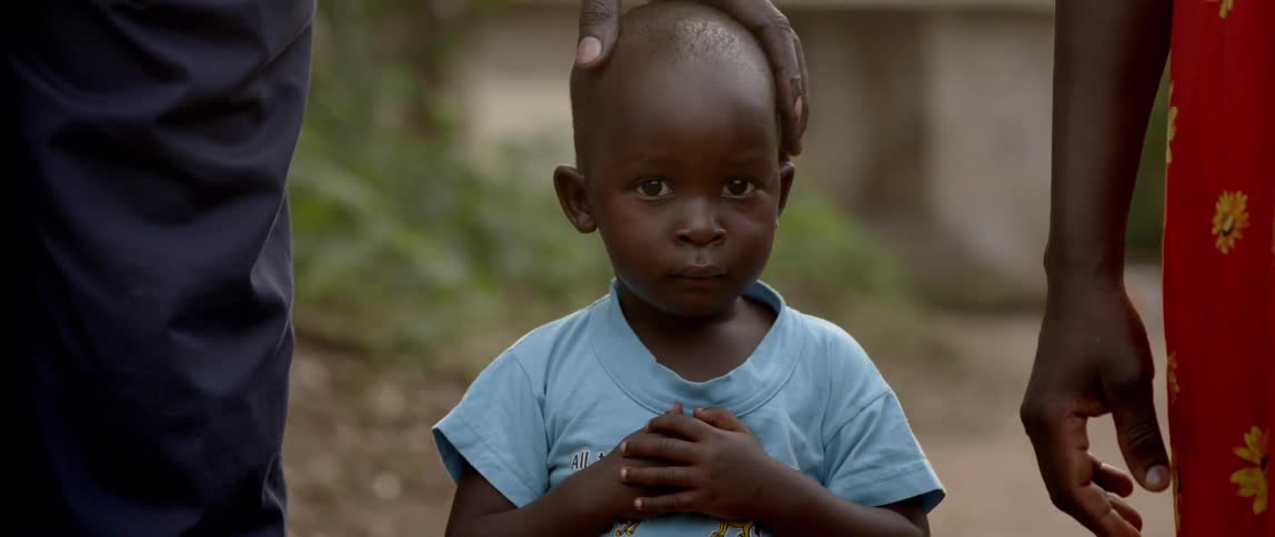 A man rests his hand on a young child's head