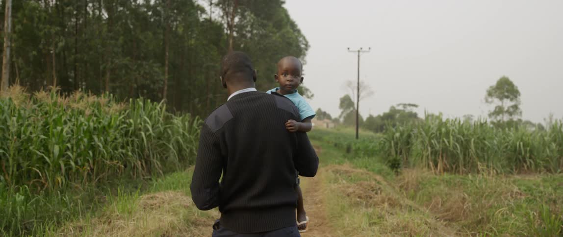 A man walks outside carrying a young boy