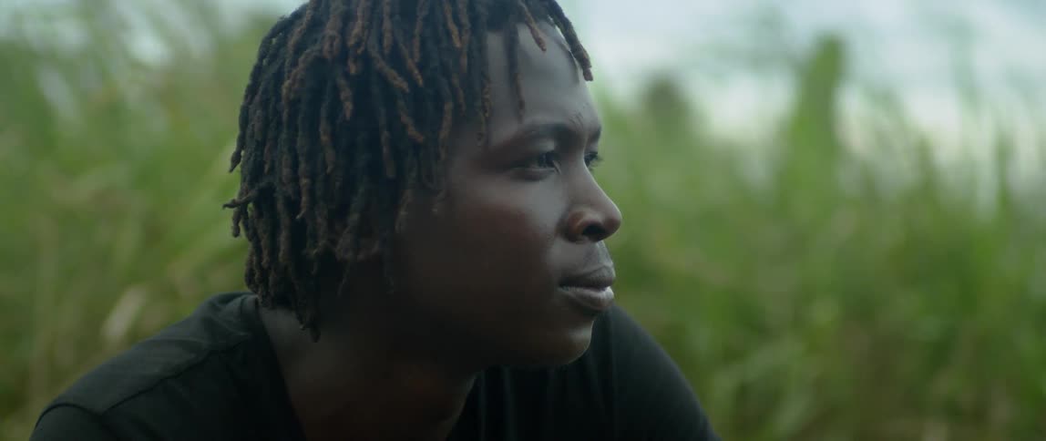 A man sits outside near vegetation