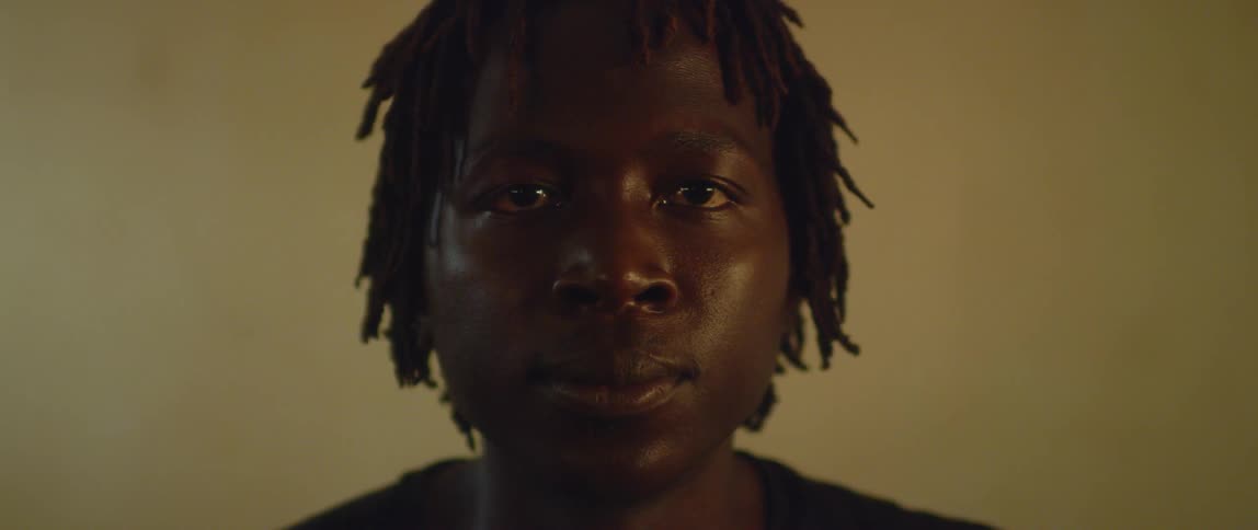 A man is staring forward in a dark room