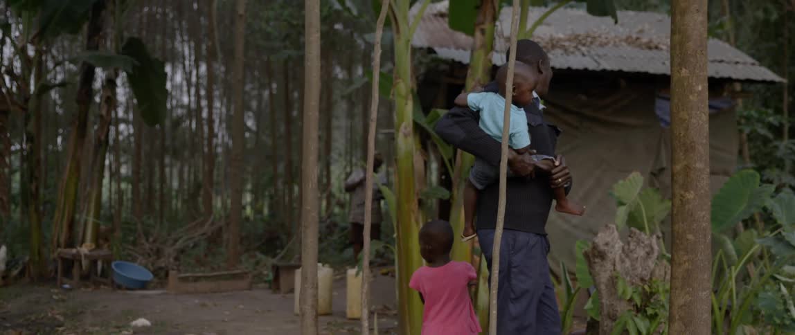 A man carries his child walking by a home