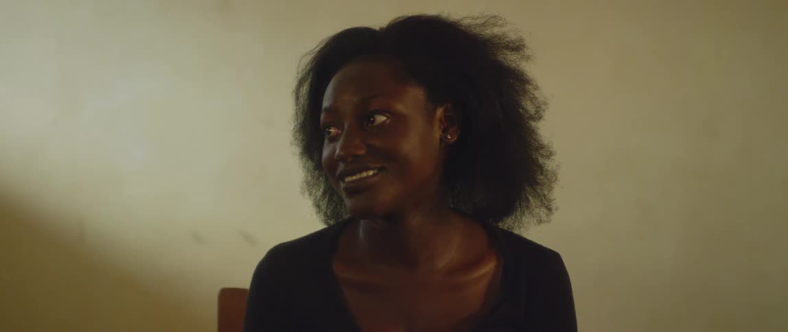 A woman stares to the side and smiles while sitting