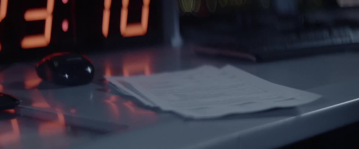 Papers are dropped onto a desk with a digital display