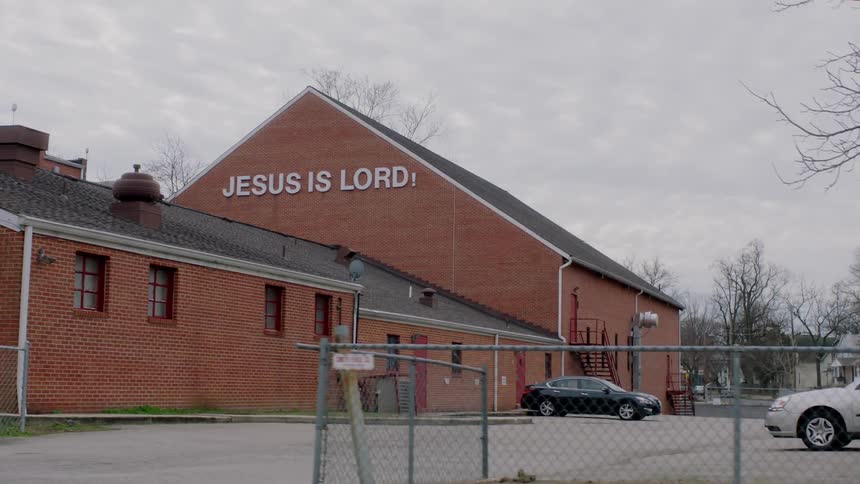 A sign is displayed on a red brick church