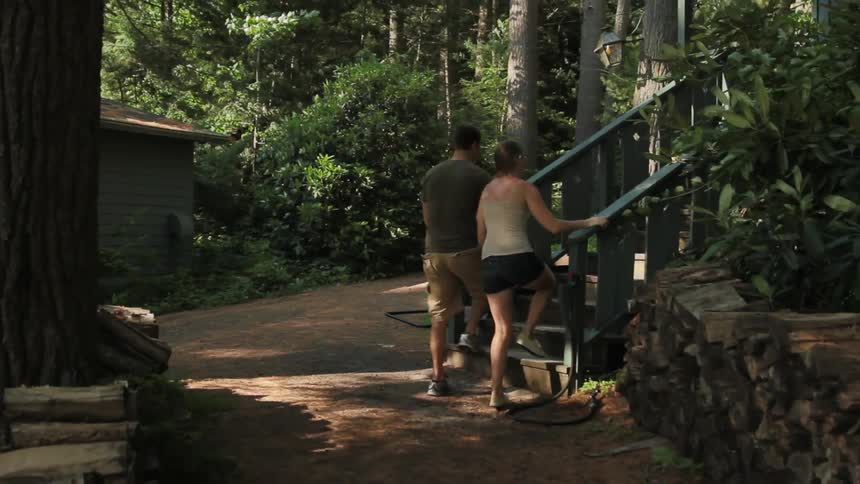 Man and woman holding hands walking then climbing steps to a home
