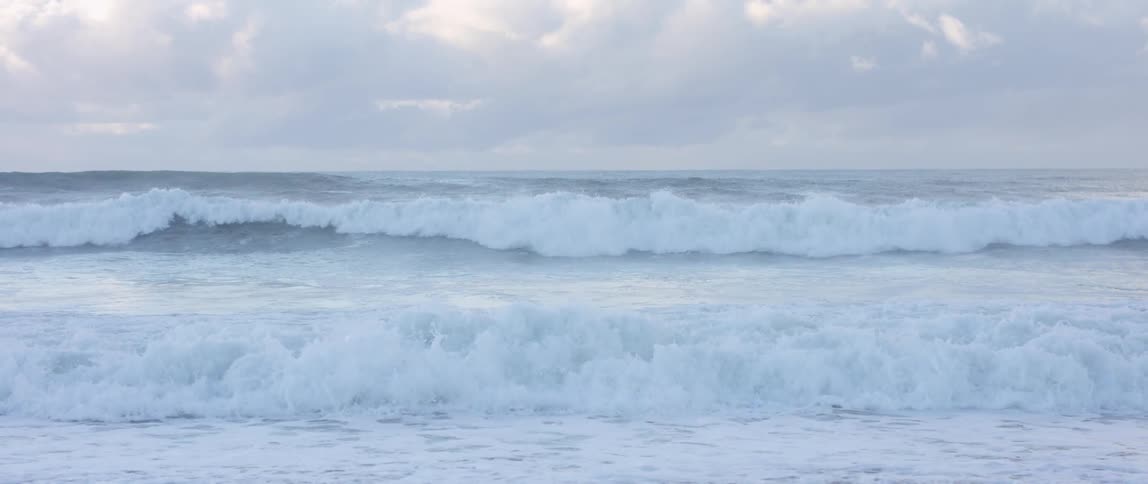 Large waves crashing into each other under a stormy sky