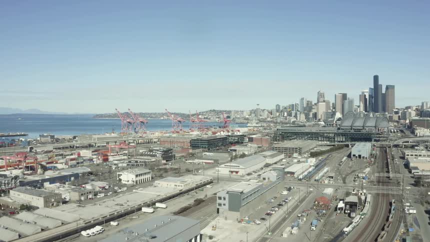 A city skyline is looming over a coastal region on a sunny day