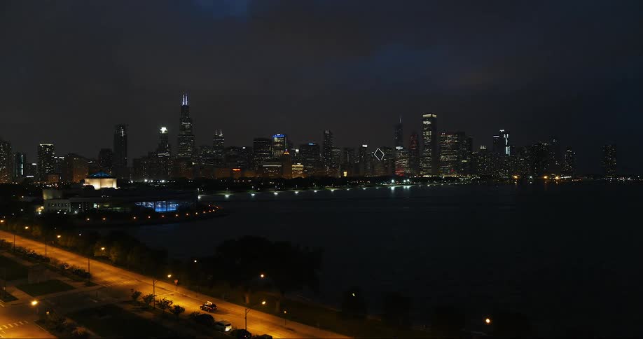 An suv is coming to a stop on a road near a harbor in a city at night