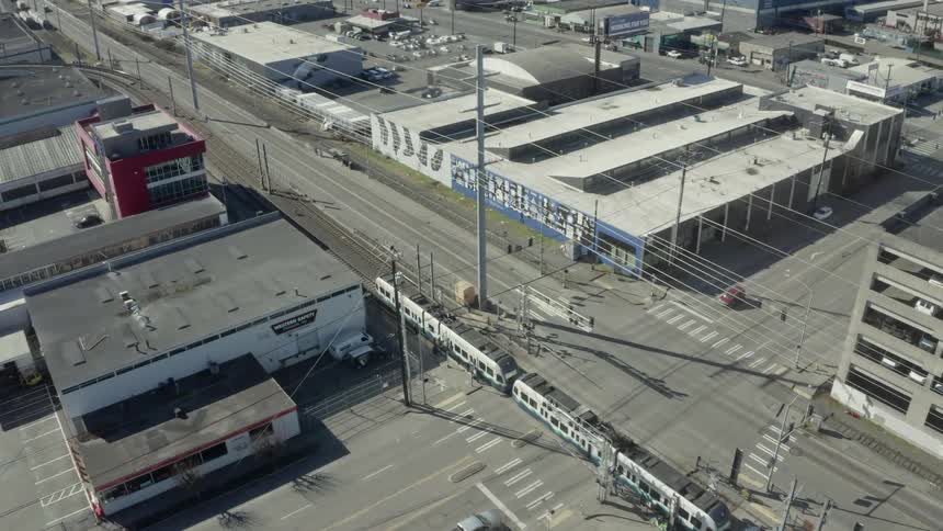 A commuter train travels down the tracks through the city