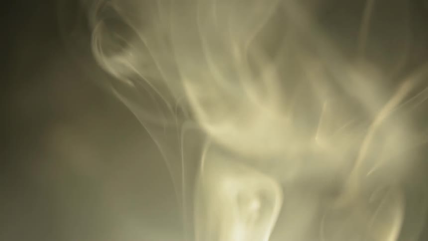Smoke billows with a light shining behind it