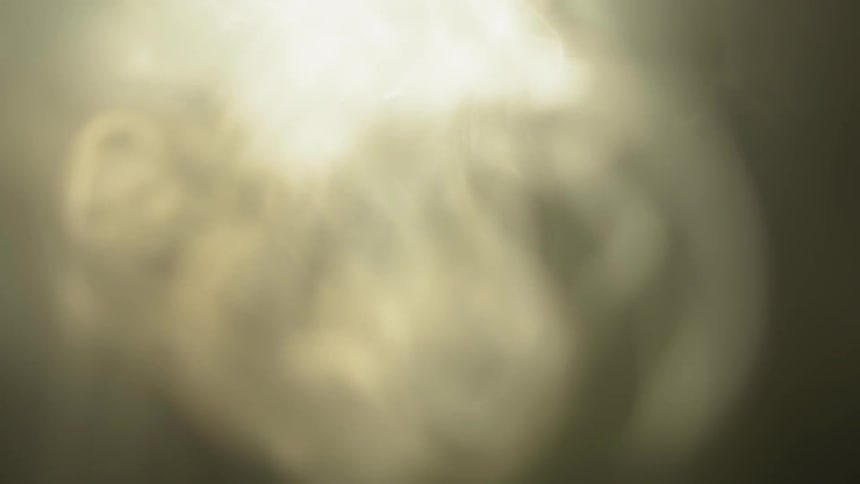 Wisps of smoke are rising and swirling in the air