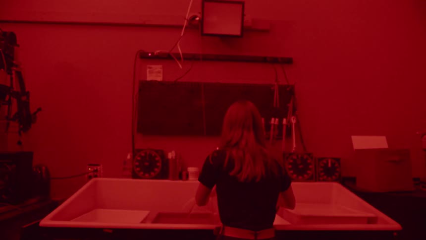 A woman develops film in a darkroom