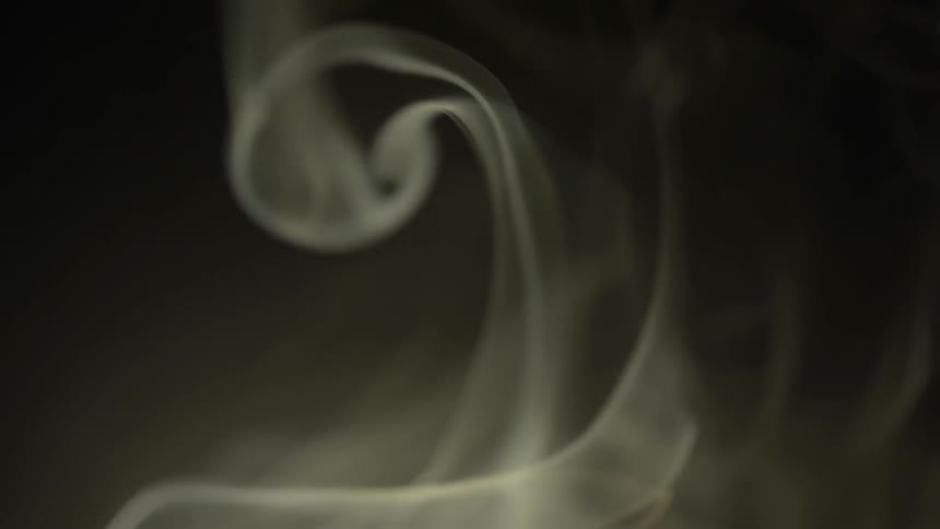 White smoke swirls against a black background