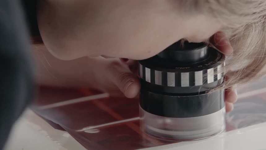 Woman looks through a magnifying glass at a picture