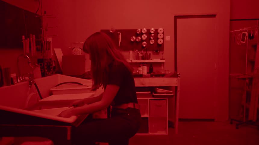 Wide shot of Woman is working with photographs in a darkroom