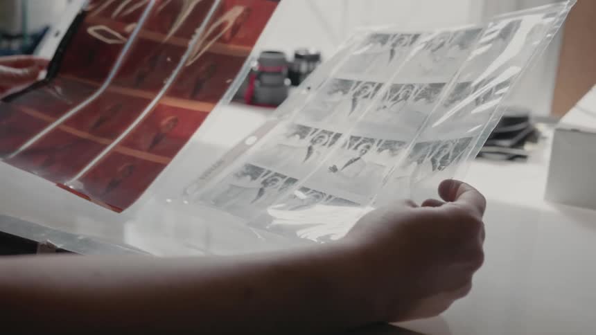 Woman looks at photo negatives near sunny window