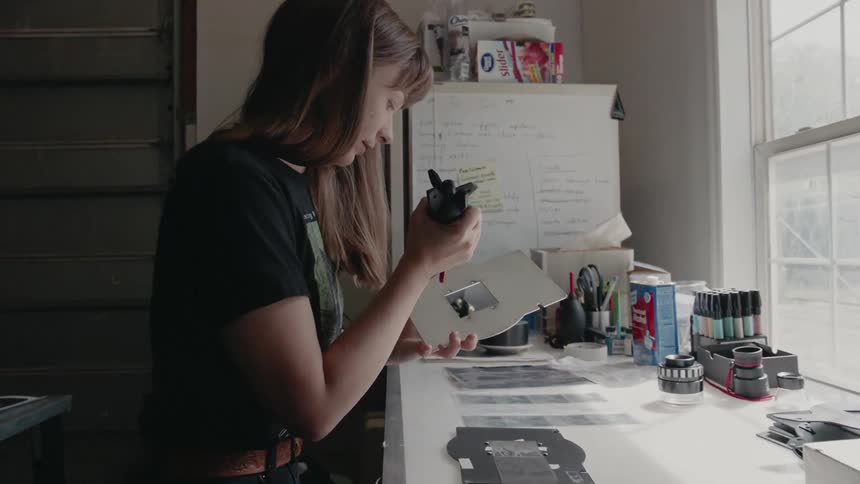 A woman uses a tool at a workbench