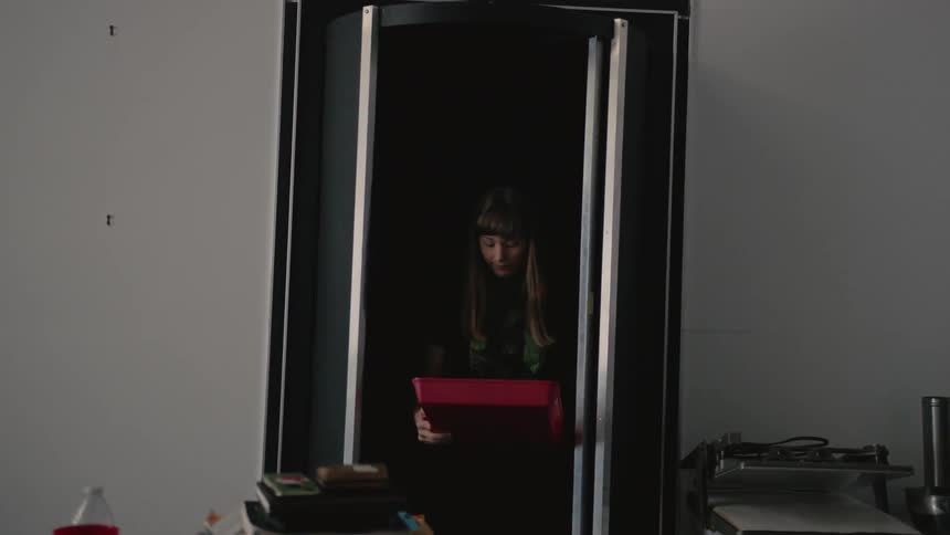 Woman walks into a room carrying a red try