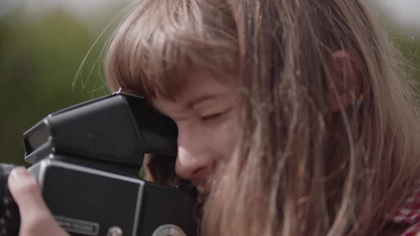 A woman takes a photograph outdoors