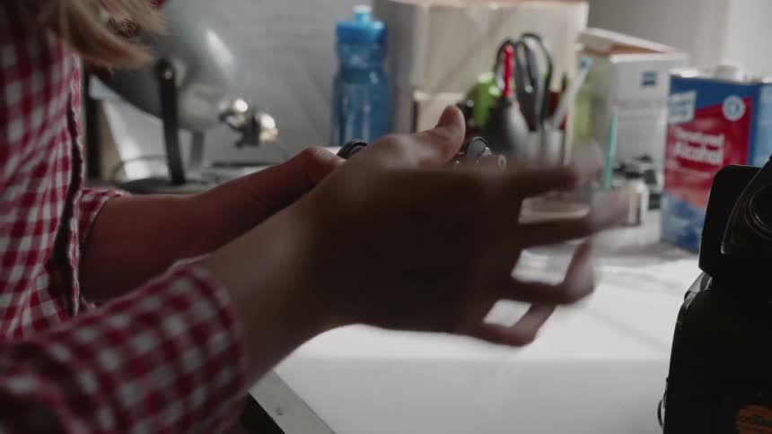 A woman adjusts pieces on a camera
