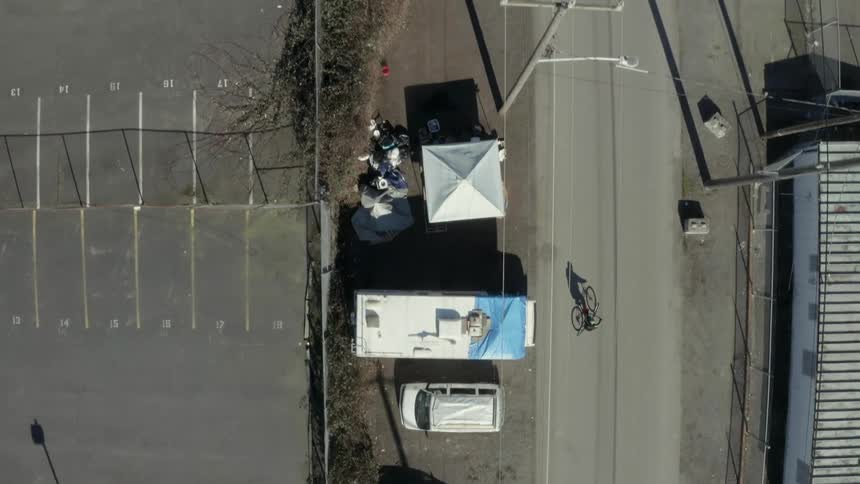 A person rides a bike past parked vans and campers