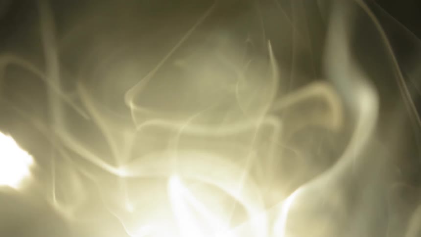 Smoke is floating around a dark room in an abstract way