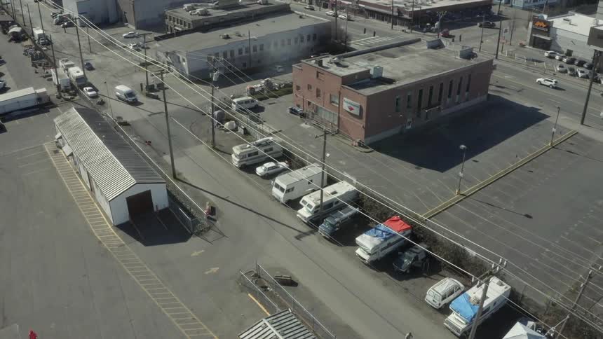 Vehicles drive on streets in a warehouse district in daylight